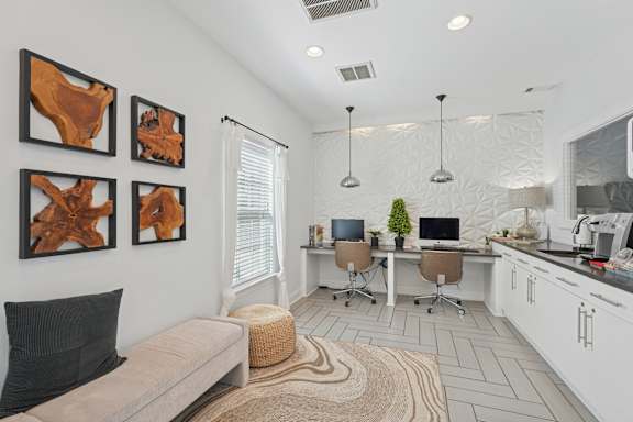 A modern living room with a couch, a desk with a computer, and three abstract paintings on the wall.