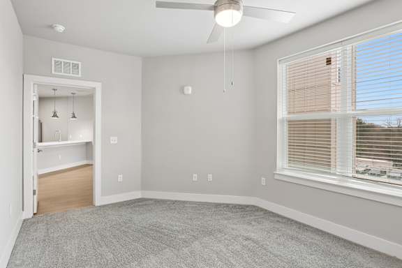 A room with a ceiling fan and a window with blinds.