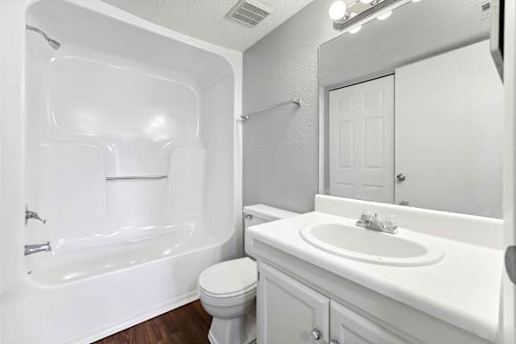 A white bathroom with a toilet, sink, and bathtub.