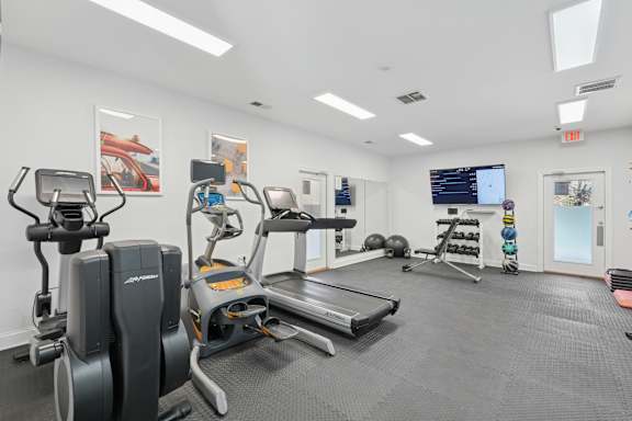 A gym with a treadmill, elliptical machines, and other exercise equipment.