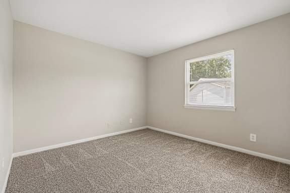 A room with a carpeted floor and a window.