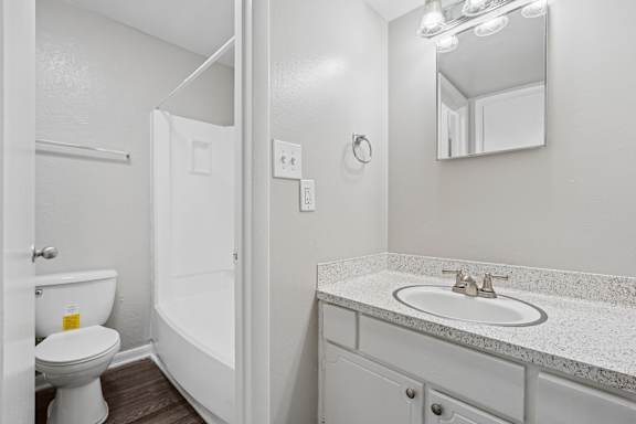 A white bathroom with a toilet, sink, and mirror.
