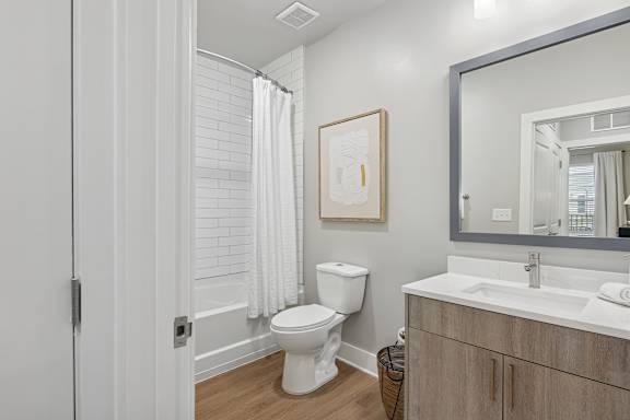 A bathroom with a toilet, sink, and mirror.