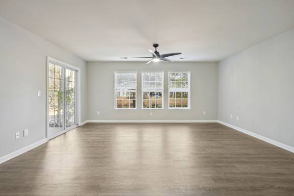 A spacious room with a ceiling fan and a wall-mounted light switch.
