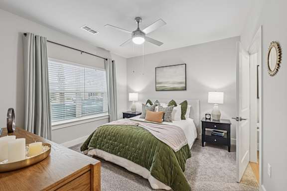 A bedroom with a bed, nightstand, and window.