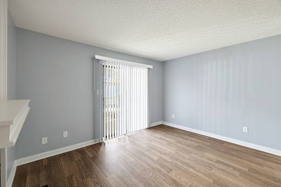 A room with wooden floors and a window with blinds.