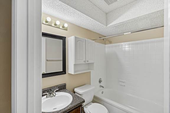 A bathroom with a white toilet, sink, and bathtub.