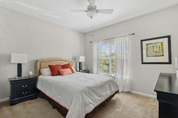 A bedroom with a bed, nightstand, and a ceiling fan.