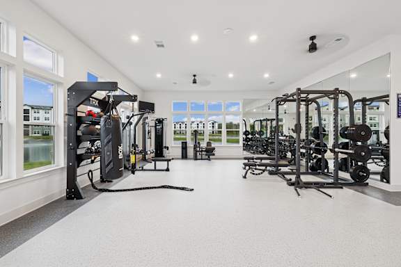 A spacious gym with a variety of equipment and a large mirror on the wall  at The Beacon at 331 Apartments, Santa Rosa Beach, FL