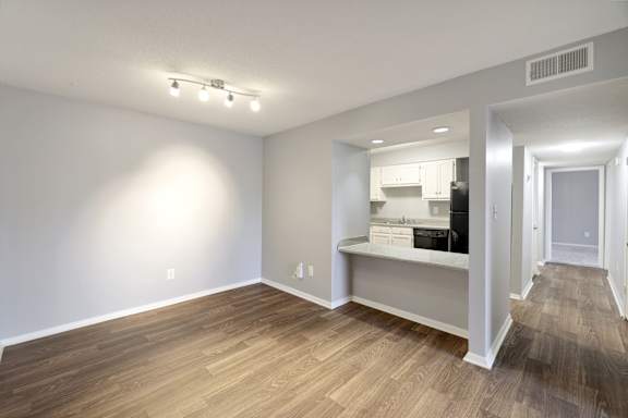 A room with a kitchenette and a long hallway.