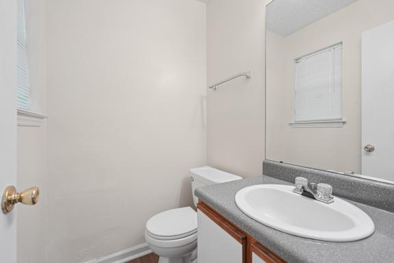 A bathroom with a toilet, sink, and mirror.