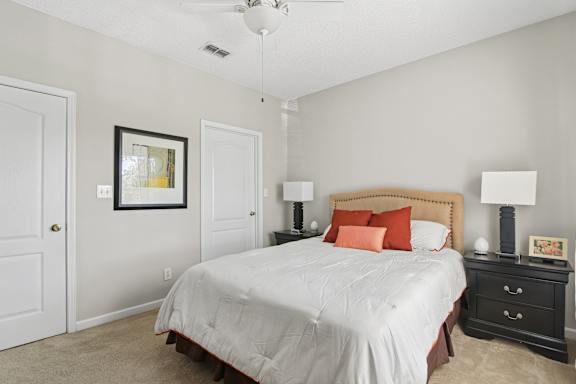 A bedroom with a bed, nightstand, and lamp.