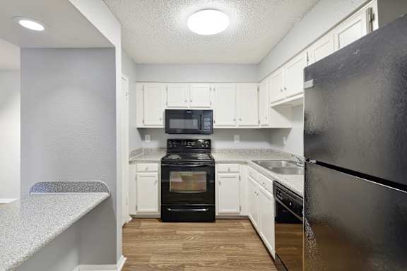 A kitchen with black appliances and white cabinets.