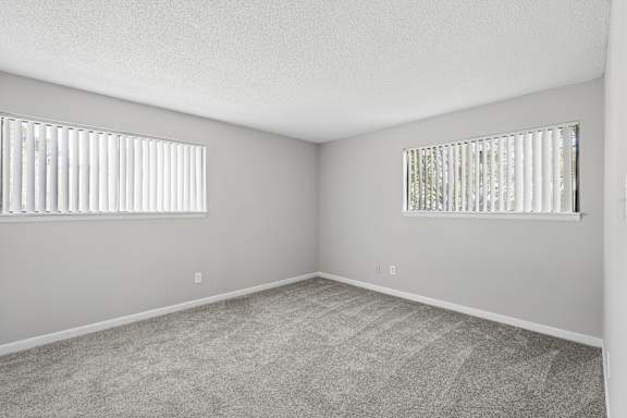 A room with two windows and carpeted floor.
