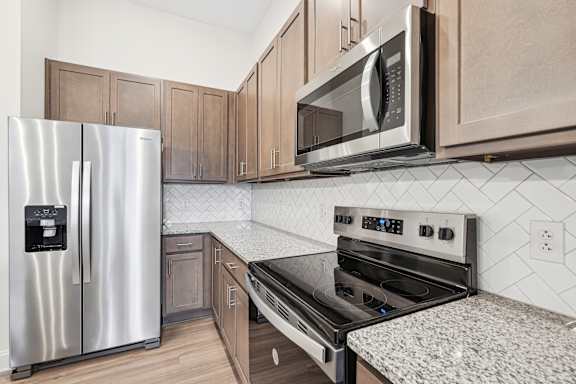 A modern kitchen with a stainless steel refrigerator, microwave, and oven.