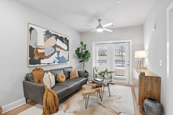 A living room with a grey couch, a brown rug, and a painting on the wall.