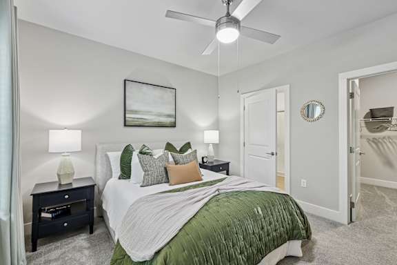 A bedroom with a bed, nightstands, and a ceiling fan.