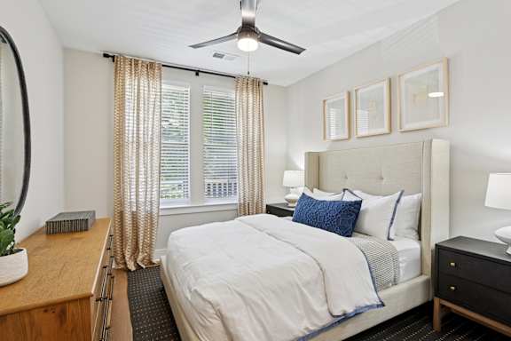 A bedroom with a large bed, a ceiling fan, and a window with curtains at Union Eleven Apartments, Georgia 30324