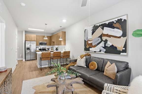 A modern living room with a grey couch and a large abstract painting on the wall.