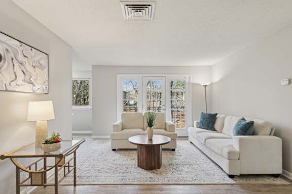 A living room with a white couch, a coffee table, and a lamp.