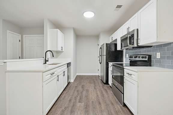 A modern kitchen with white cabinets and a black refrigerator.