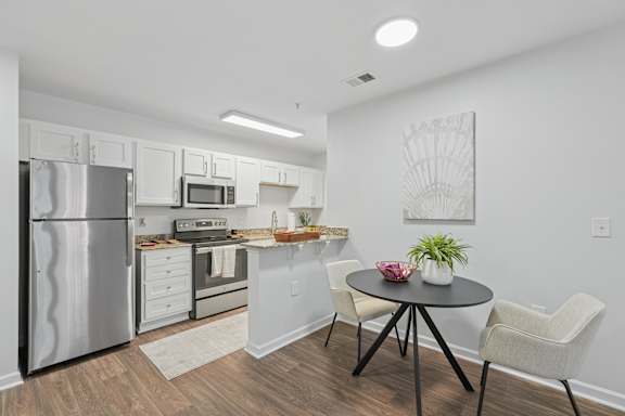 A kitchen with a refrigerator, oven, and sink.