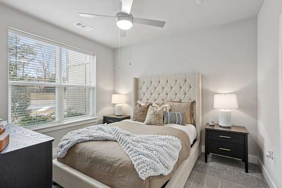 A bedroom with a large bed and a ceiling fan.