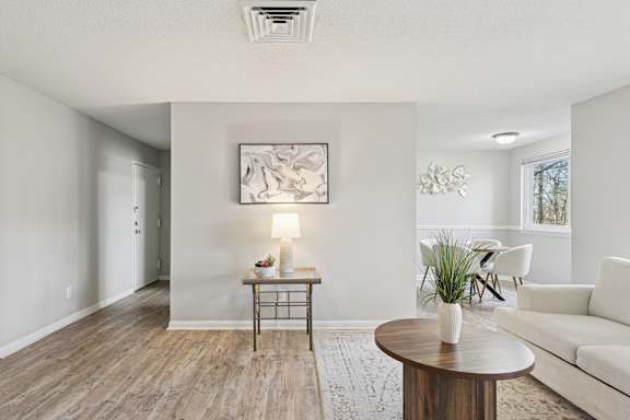 A living room with a white couch, a wooden table, and a painting on the wall.