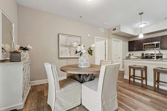A dining room with a table set for two and a kitchen in the background.