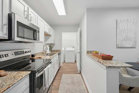 A kitchen with black appliances and white cabinets.