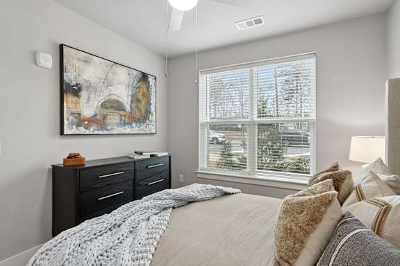 A bedroom with a large bed and a painting on the wall.