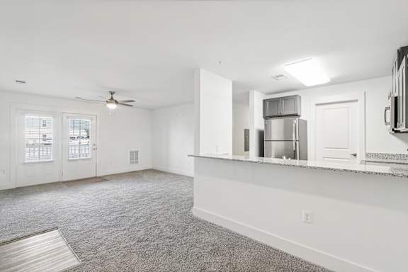 A spacious room with a ceiling fan and a kitchenette in the background at The Parker North Augusta, North Augusta, SC, 29841
