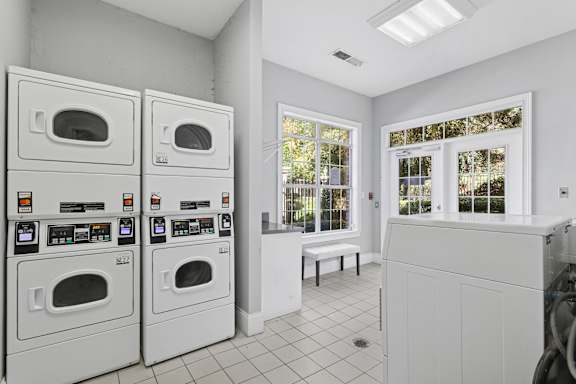 A laundry room with two washing machines and a bench.