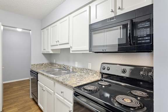 A kitchen with black appliances and white cabinets.