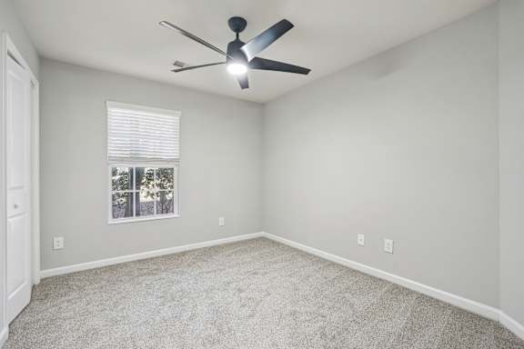 A room with a ceiling fan and a window with blinds.