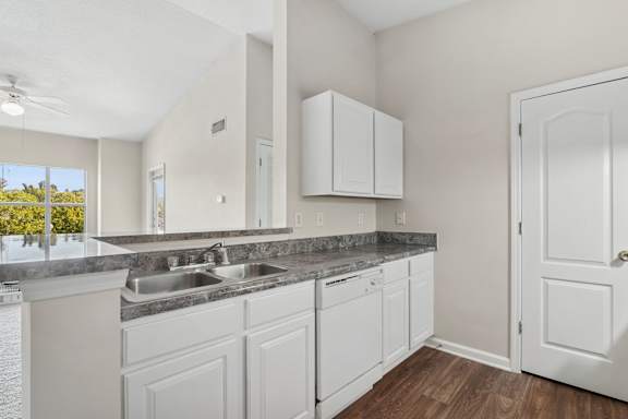 A kitchen with white cabinets and a marble countertop.