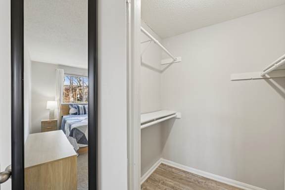 A bedroom with a bed, nightstand, lamp, and a mirror.