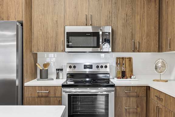 A modern kitchen with a stainless steel refrigerator, a microwave, and a stove top oven.
