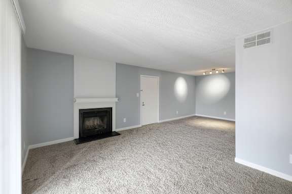 A living room with a fireplace and carpeted floor.