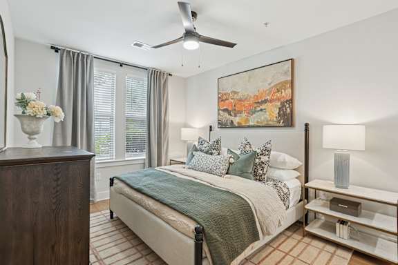 A bedroom with a bed, a dresser, and a painting on the wall at Union Eleven Apartments, Atlanta