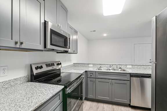 A kitchen with a stove, microwave, and refrigerator at The Parker North Augusta, North Augusta, SC, 29841