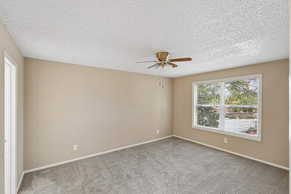A room with a ceiling fan and a window showing an outdoor view.