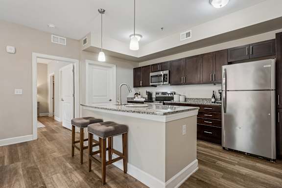 A kitchen with a white counter top and a stainless steel refrigerator.