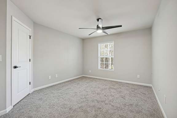 A room with a ceiling fan and a window with blinds.