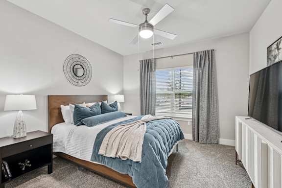 A bedroom with a bed, nightstand, and window.