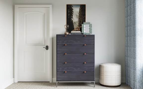 A dark blue chest of drawers sits next to a white door at The SoHo Luxury Apartments, North Carolina