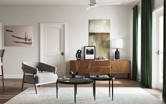A modern living room with a grey armchair, a glass table, and a wooden cabinet at The SoHo Luxury Apartments, Raleigh, North Carolina
