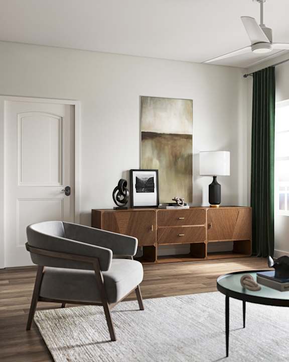 A modern living room with a grey armchair, a wooden cabinet at The SoHo Luxury Apartments, North Carolina 27603
