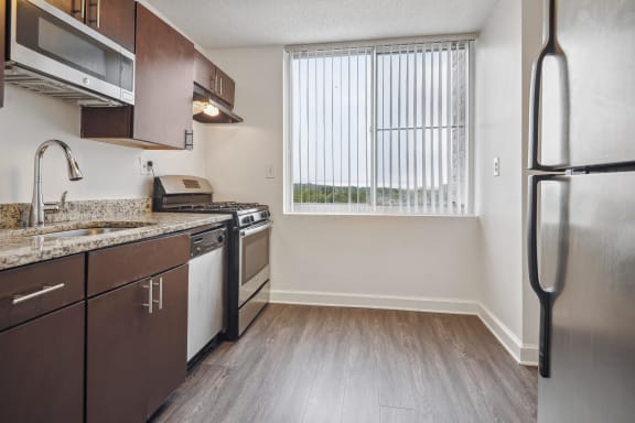 an empty kitchen with stainless steel appliances and a window