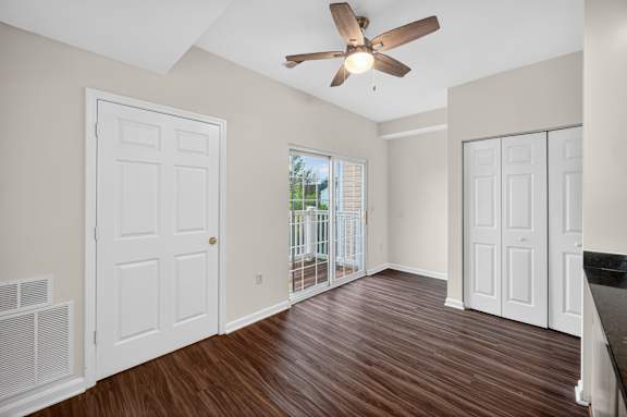 A room with a ceiling fan and sliding glass doors.